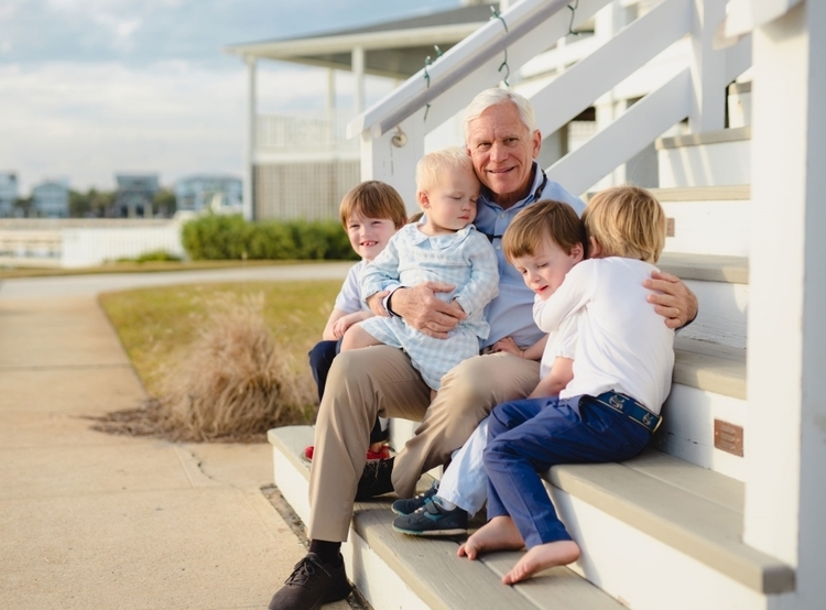 Reid Murchison sitting on porch steps with grandchildren