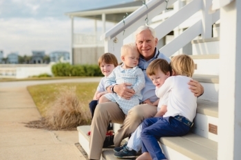Reid Murchison sitting on porch steps with grandchildren